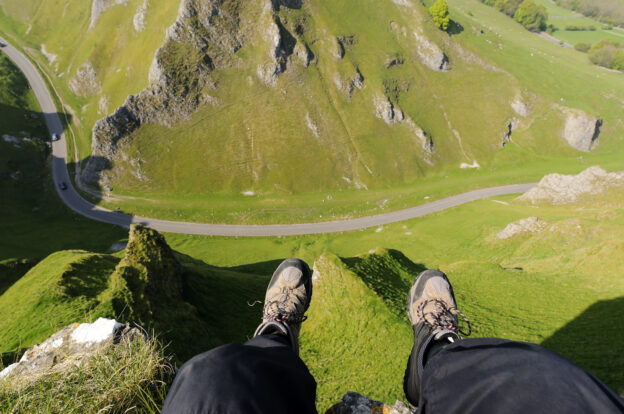 Shot looking down at walkers feet hanging over edge of above Winnats Pass