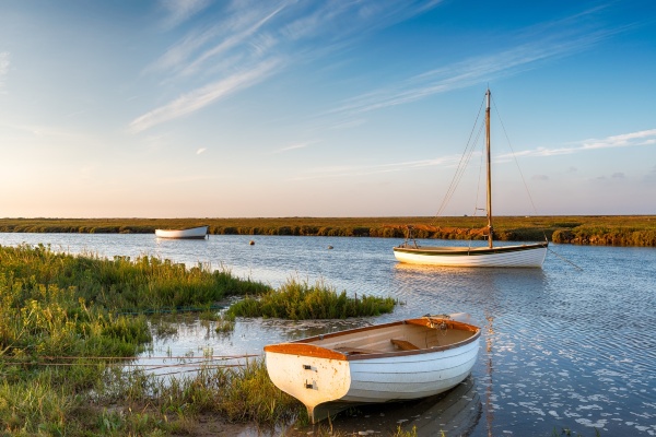 Boats at high tide on salt marshes at Blakeney on the norfolk coast